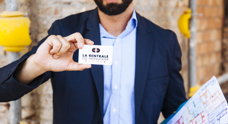 Homme tenant une carte de visite 'La centrale du menuisier'